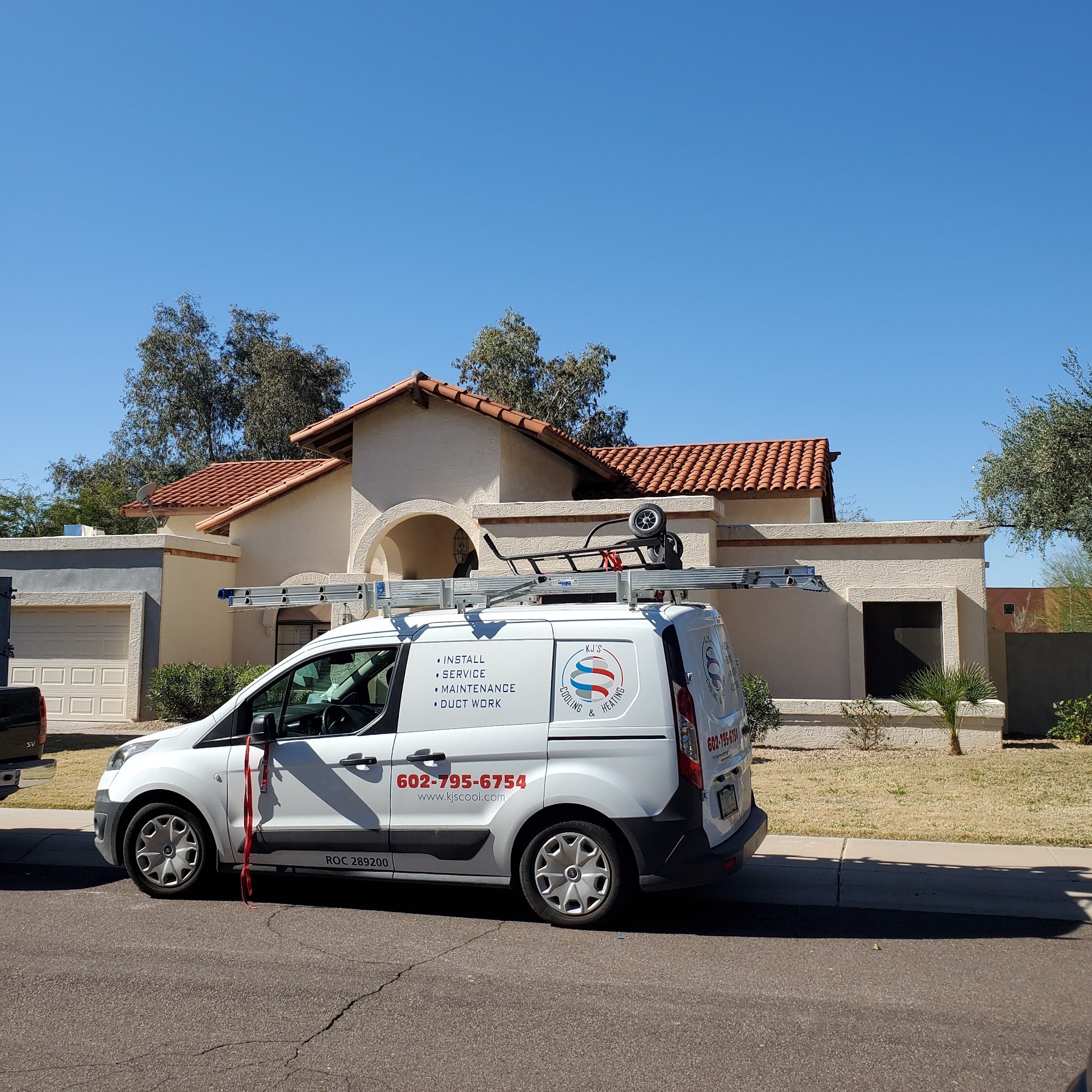 KJ's Cooling & Heating service van with ladders parked outside a Phoenix home