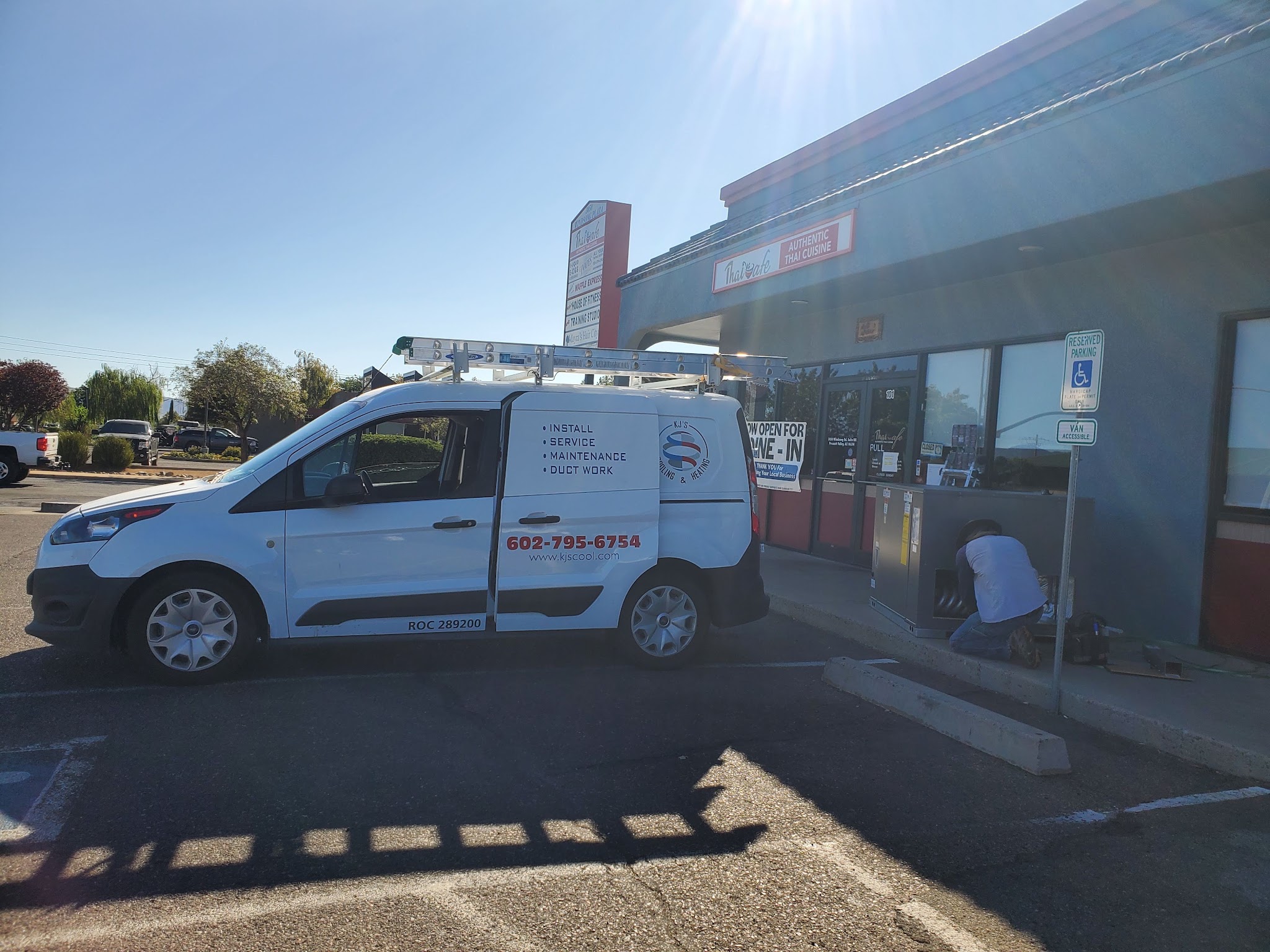 KJ's van at a commercial plaza while a technician works on site